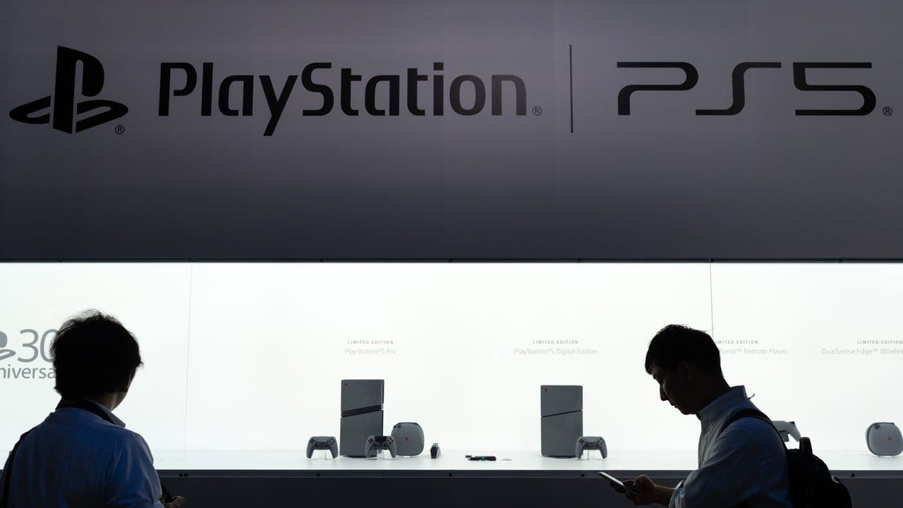 A stack of PlayStation disc game cases next to a PS5 console on a shelf