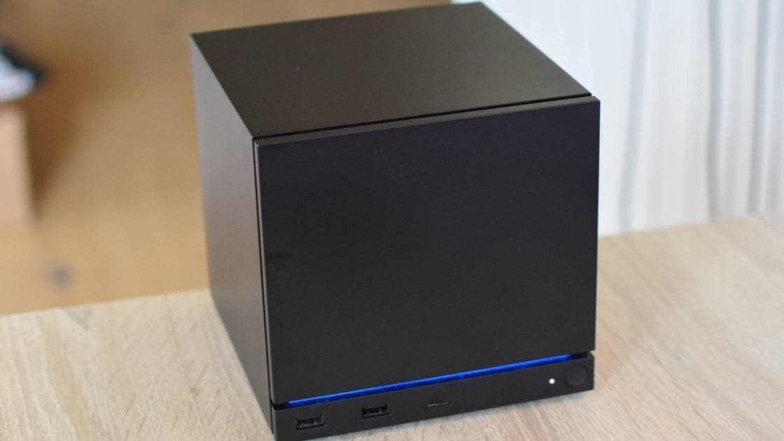 Valve Steam Machine console sitting on a desk next to a Steam Controller